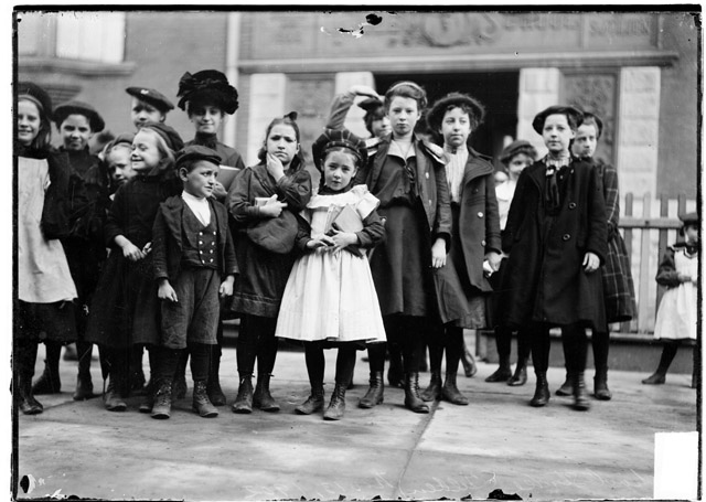 School strike, a group of children and a woman assembled on a sidewalk in front of a Tilden school entrance