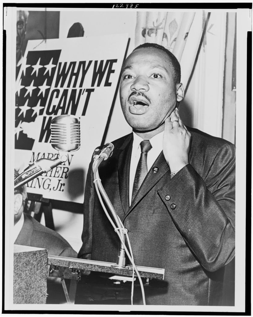 Martin Luther King, Jr., three-quarter-length portrait, standing, facing front, at a press conference