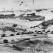 Bird's-eye view of landing craft, barrage balloons, and allied troops landing in Normandy
