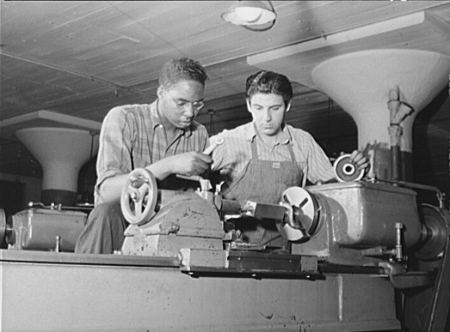 Two young men of the Civilian Conservation Corps working together on a machine
